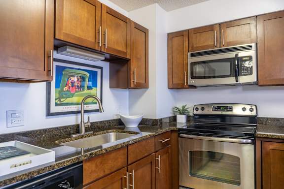 A kitchen with brown cabinets and a painting of a family in the background.