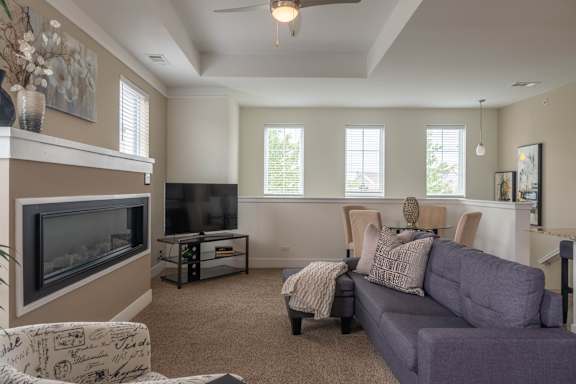 A living room with a grey couch and a fireplace.
