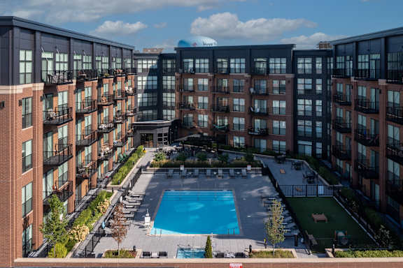 A patio area with a couch and chairs in front of a brick building.