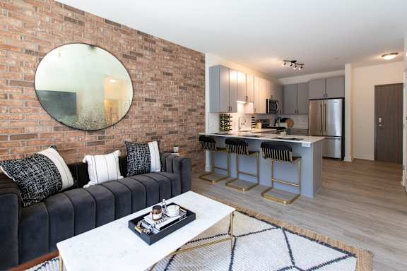 A modern living room with a brick wall and a round mirror.