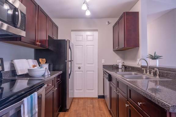 A kitchen with dark brown cabinets and a black counter top.