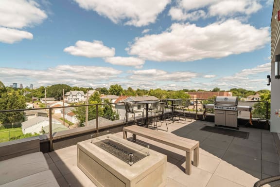 a rooftop patio with a grill and picnic table