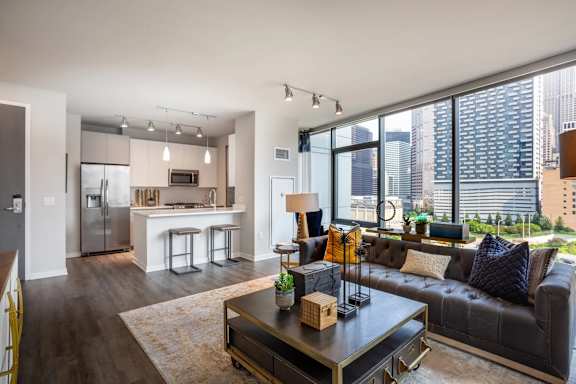 A modern living room with a black leather couch and a coffee table in the center.