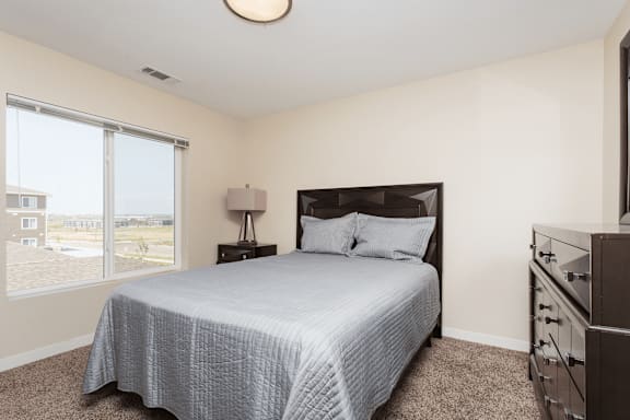 a bedroom with a ceiling fan and a bed with a blue and white comforter