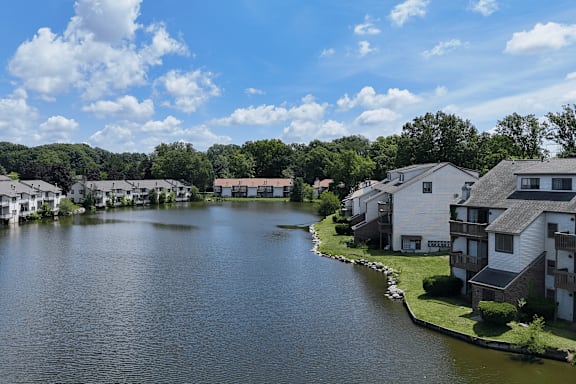 A serene lake surrounded by residential buildings under a clear blue sky.