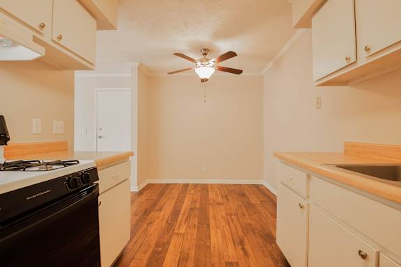 A kitchen with a black stove top oven and wooden floors.