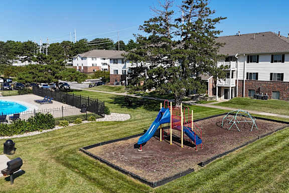 A playground with a blue slide and a red swing set.