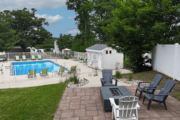 A backyard with a pool and patio furniture.