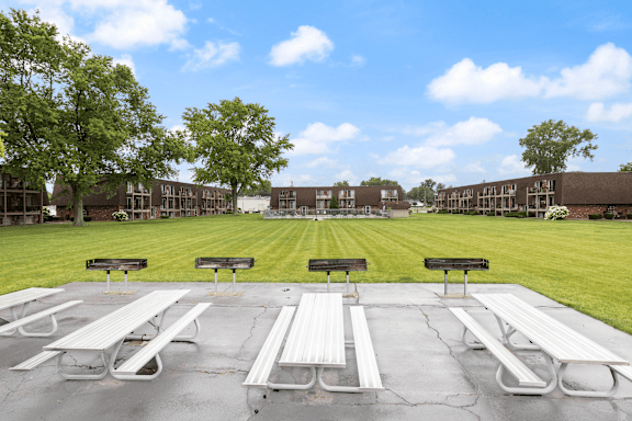 A picnic area with benches and tables in front of a building.