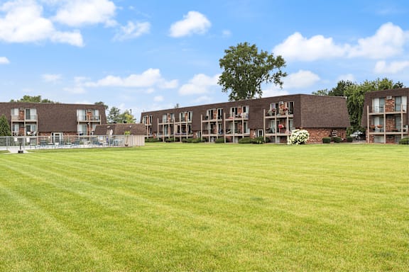 A grassy field in front of apartment buildings.