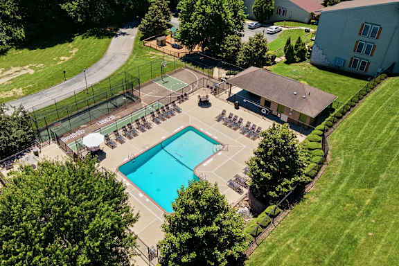 An aerial view of a pool surrounded by trees and a building.