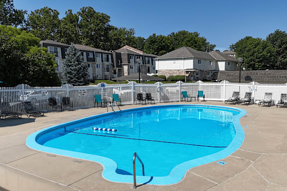 A large blue swimming pool surrounded by a white fence.