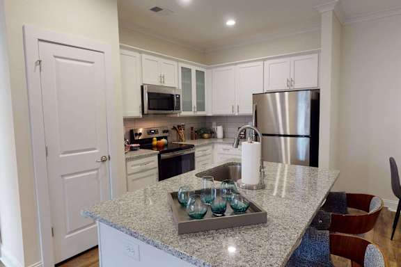 A kitchen with a granite countertop and stainless steel appliances.