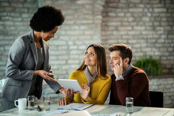 Two people are sitting on a windowsill with their feet up, holding a cup of coffee and a book.