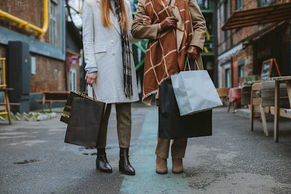 Two women walking down the street carrying shopping bags.