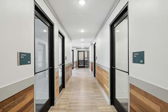A long hallway with doors on both sides and signs above them. at Vintage Raleigh West Apartments, Raleigh, NC
