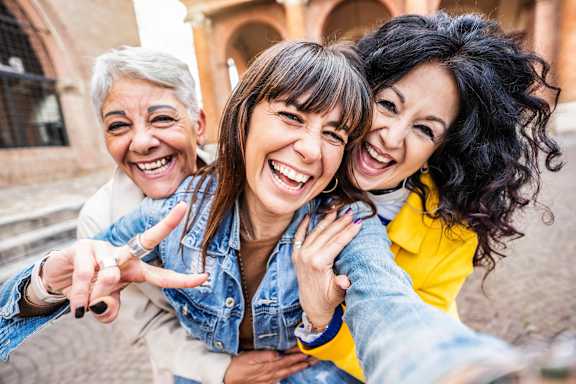 Two women are taking a selfie with a third person.