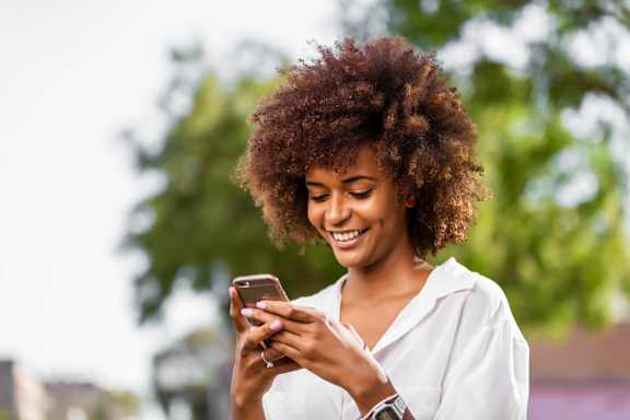 A woman is looking at her smartphone at Lakeside Villas Apartments, Hampton, GA