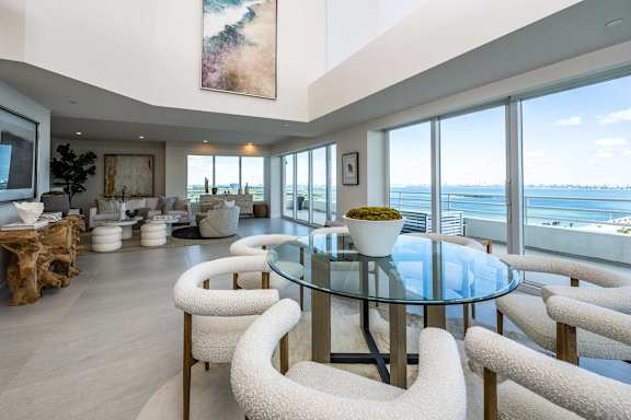 a living room with a glass table and chairs and a view of the ocean at The Hamilton Apartments, Miami, FL 33137