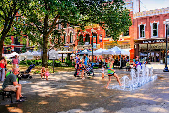 A woman is playing in a fountain in a city square.