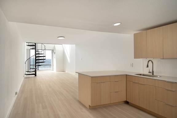 A kitchen with wooden cabinets and a black metal staircase.