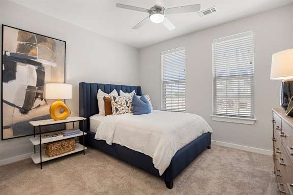 A bedroom with a bed, nightstand, and a ceiling fan.