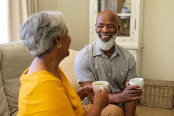 a man and a woman sitting on a couch holding coffee cups