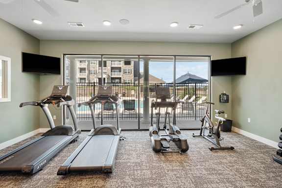 A gym with treadmills, elliptical machines, and a television.