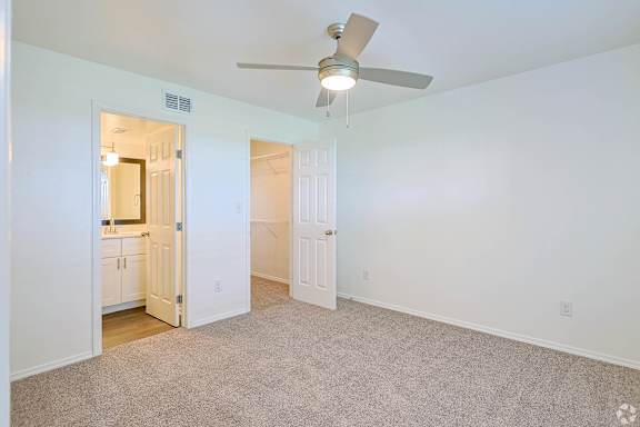 A room with a ceiling fan and carpeted floor.