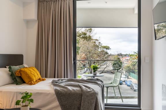 a bedroom with a bed and a balcony and a large window