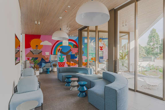 a lobby with blue couches and chairs and a colorful mural