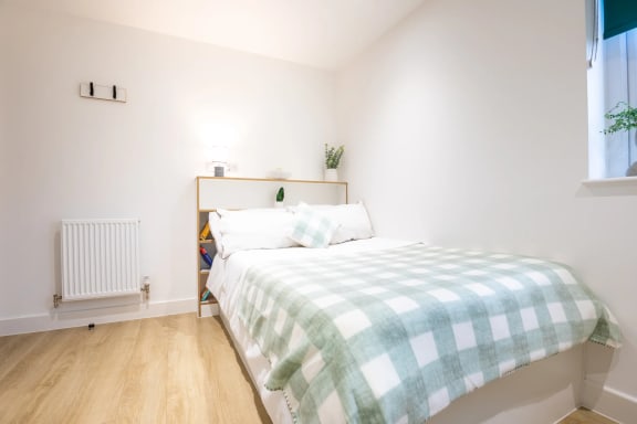 a bedroom with a bed and a green and white bedspread