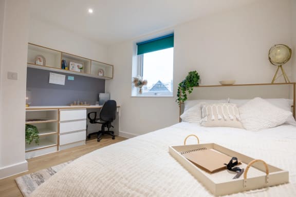 a bedroom with a bed and a desk and a window
