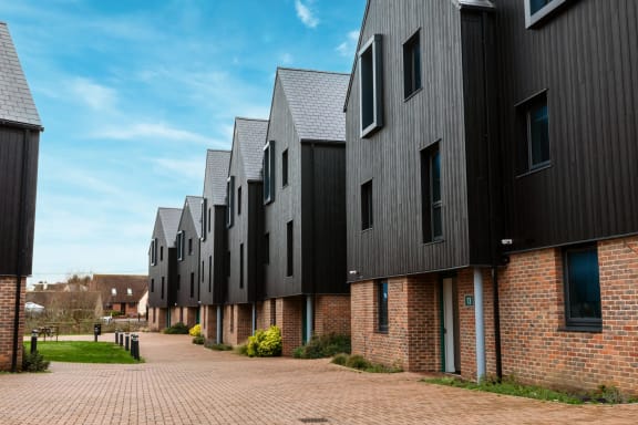 a row of houses with black roofs and a brick sidewalk