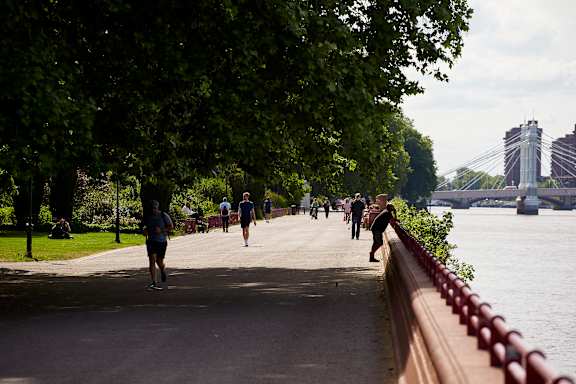 A group of people are walking along a path next to a river.