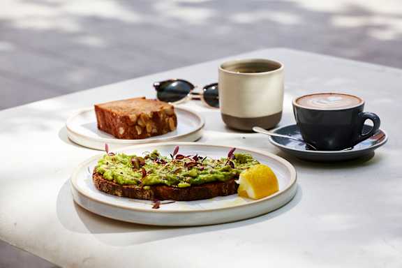 A table with two plates of food and a cup of coffee.