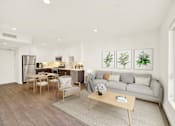Thumbnail 29 of 41 - A modern living room with a grey sofa, wooden coffee table, and a kitchen area in the background.