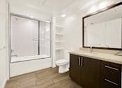 Thumbnail 39 of 41 - A bathroom with a toilet, sink, and a bathtub with a glass door.