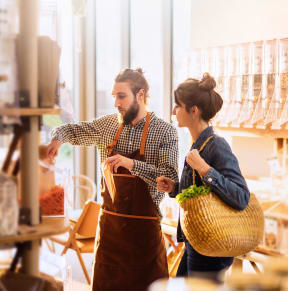 a man and a woman in a grocery store with a basket of food