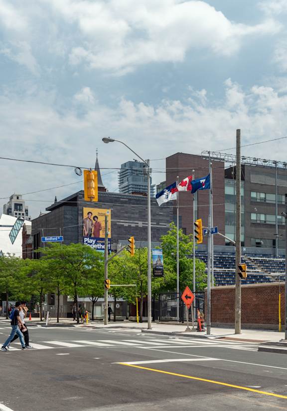 people crossing the street at an intersection in a city with tall buildings at 161 St. George, Toronto California