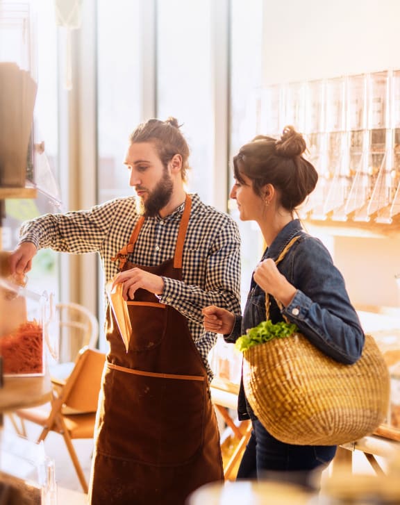 a man and a woman in a grocery store with a basket of food