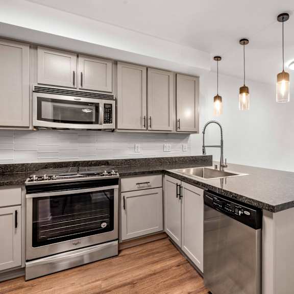 a kitchen with granite countertops and wooden cabinets at 128 on State Apartments in Kirkland, Washington 98033
