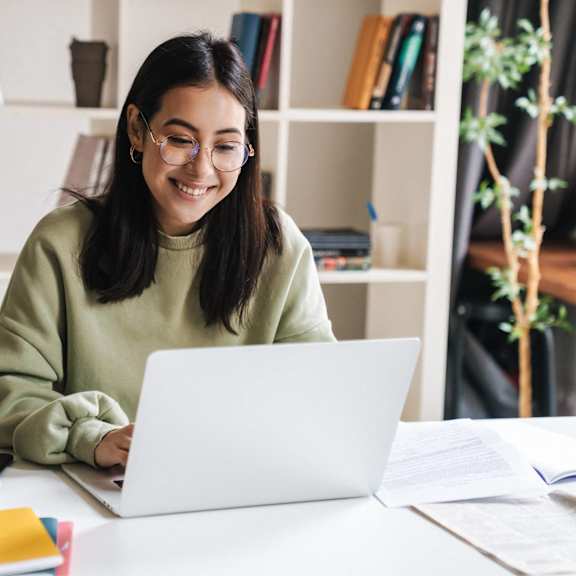 portrait of a smiling young woman holding books and cell phone