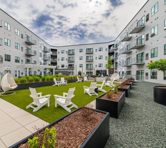 an open courtyard with chairs and tables in front of an apartment buildingat Northern Lights a Lifestyle-Driven Community, West Fargo, ND