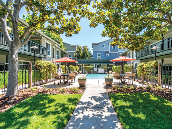 a courtyard with tables and umbrellas and a swimming pool  at Pleasanton Glen Apartments, California, 94566