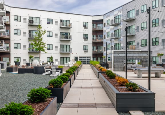 a communal area with benches and plants in front of an apartment building at Northern Lights a Lifestyle-Driven Community, West Fargo, North Dakota