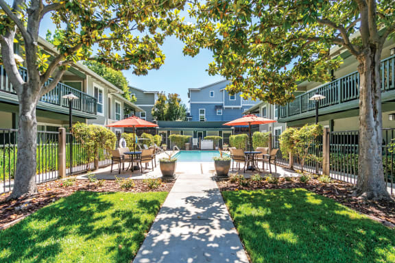 a courtyard with tables and umbrellas and a swimming pool  at Pleasanton Glen Apartments, California, 94566