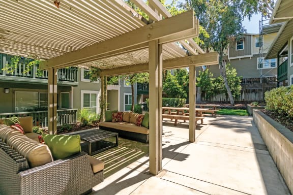 a covered patio with furniture and a wooden pergola at Pleasanton Glen Apartments, California