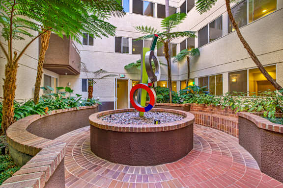 A circular brick patio with a fountain in the middle at Peach Tree Court, Los Angeles, CA 90024
