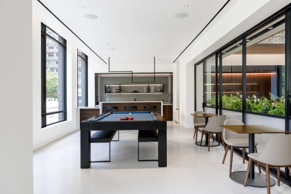 a black pool table in the middle of a room with tables and chairs